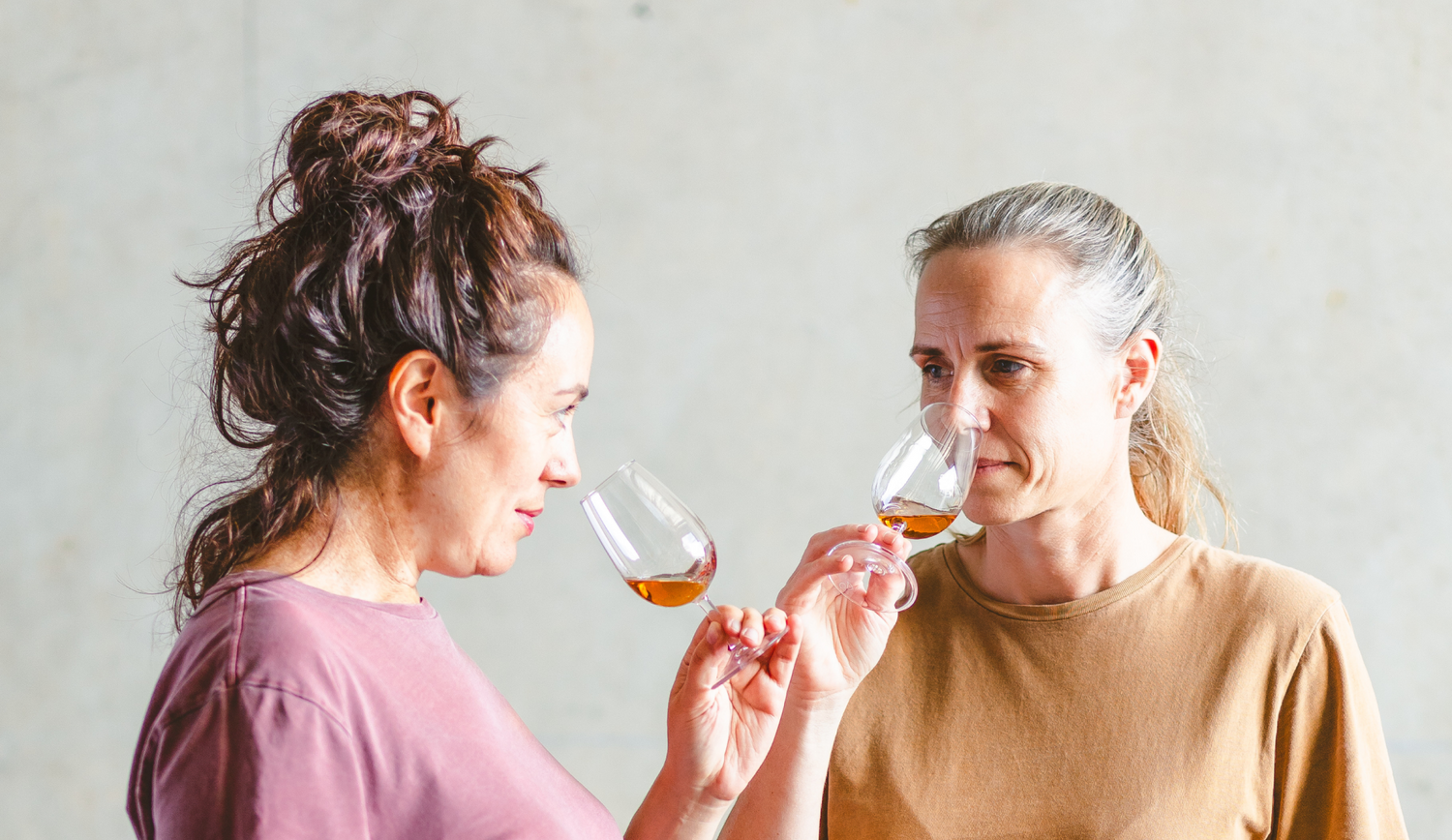 Two women smelling rum.